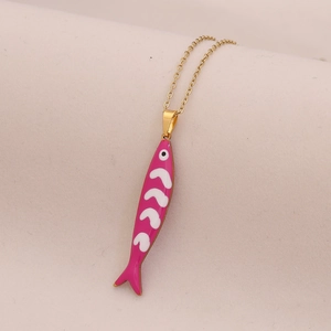 Gold stainless steel necklace with pink and white enamel fish pendant on fabric