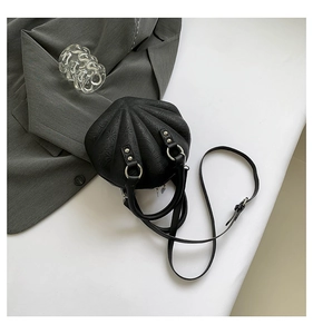 Detailed macro view of black embossed shell bag featuring silver metal fasteners