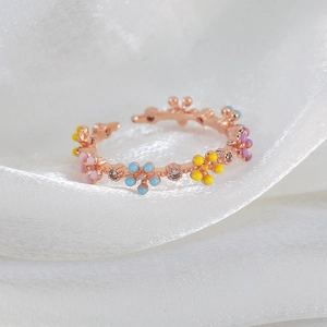 Detailed shot of macaron enamel flowers and white zircon on a rose gold open ring