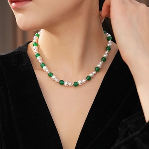 Primo piano di una collana vintage con perle e agata verde su modella, stile girocollo chic