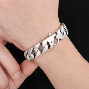Detailed close-up of 15mm antique silver Cuban chain bracelet on wrist with dark background