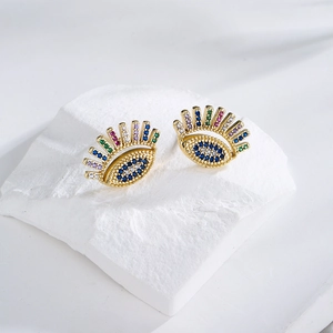 Golden eye shaped earrings with colorful zircon inlay on white textured stone