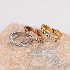 Crossed X-shape stainless steel rings with shimmering pavé diamonds in three metal colors