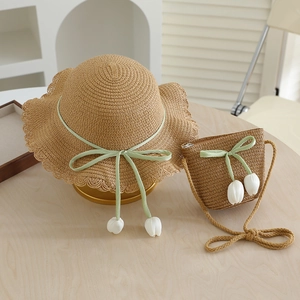 Detailed view of woven straw sun hat and matching bag with green ribbons and tulips