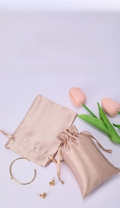 Champagne satin drawstring pouch for jewelry storage with elegant silk texture and gold accents