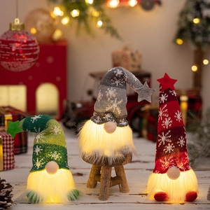 Three Christmas gnomes with LED lights on a wooden surface in a festive holiday setting