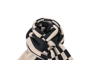 Close-up of knit scarf showing black and beige checkerboard texture and soft wool yarns