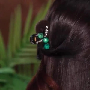 Detail of a small green bead hair claw clip holding long dark brown hair with rhinestones