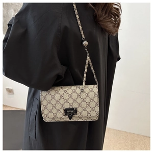 Close-up of geometric pattern crossbody bag with chain strap and metal lock detail