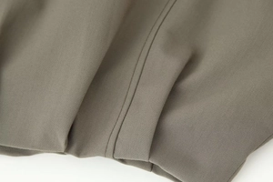 Macro shot of high-density olive green bomber jacket fabric and durable double stitching