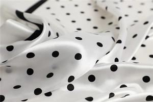Close-up of elegant white satin silk scarf with classic black polka dot pattern details