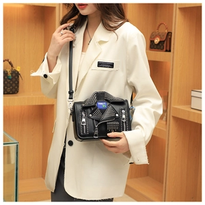 Detailed view of punk style jacket shaped shoulder bag with silver studs and zippers