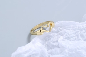 Detailed view of a golden metal ring featuring a unique creative heart hand gesture design