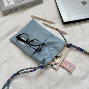 Detail of light blue corduroy crossbody bag with rabbit embroidery and woven strap