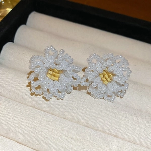Macro shot of handcrafted flower stud earrings made with white and yellow seed beads