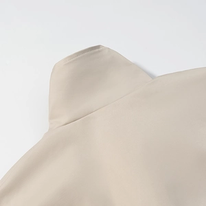 Close-up of beige trench coat stand collar showing detailed stitching and fabric texture