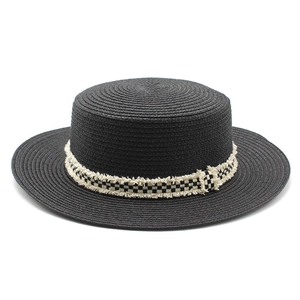 Détail d'un chapeau de paille noir avec ruban damier effiloché et tissage serré