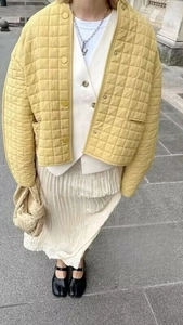 Detailed street style of a yellow quilted short jacket paired with a white pleated skirt