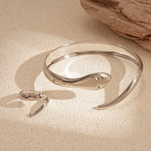 Detail of silver snake-shaped open bracelet and ring set with crystal eye accents