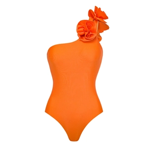 Detailed view of 3D floral applique on vibrant orange one-shoulder swimsuit fabric