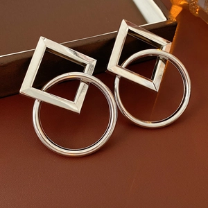 Détail de boucles d'oreilles argentées géométriques avec formes carrées et rondes entrelacées