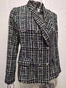 Dettaglio della trama in tweed pied-de-poule bianco e nero con bottoni metallici doppiopetto
