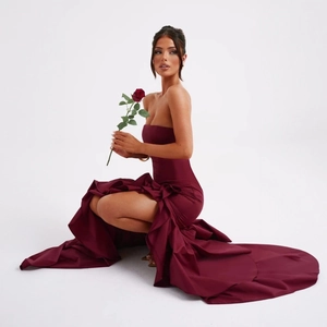 Detail of burgundy off-shoulder evening gown featuring ruffled hem and high leg slit