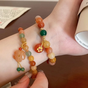 Detailansicht von Perlenarmbändern mit Blumenanhängern am Handgelenk im warmen Licht
