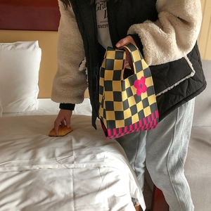 Close-up of knit tote bag with yellow checkered pattern and pink flower design details