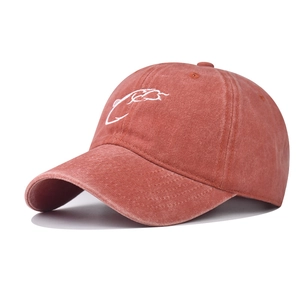 Macro detail of the white embroidery on washed brick-red cotton baseball cap surface