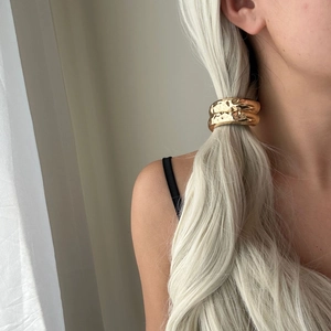 Close-up of golden hammered metal ponytail wrap hair accessory on blonde hair