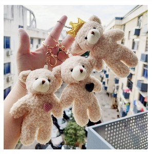 Close-up of beige plush teddy bear keychains with gold crowns and heart charms
