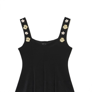 Elegant black sleeveless top with gold and pearl 3D flower accents, flat lay view