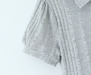 Dettaglio dell'abito in maglia grigia con maniche a sbuffo e colletto elegante