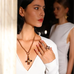 Close-up of golden cross necklace and matching ring with purple stones and pearls