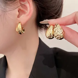 Minimalist twisted golden hoop earring set with teardrop and hammered studs on model