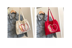 Detail of nylon drawstring tote bags featuring apple prints in white and red colors