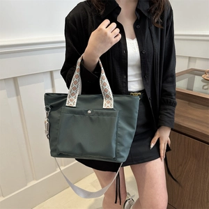 Deep green nylon tote bag with patterned handles and wide shoulder strap for daily commuting