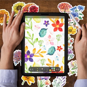 Close-up of floral watercolor stickers on a desk with a tablet and a creative hand