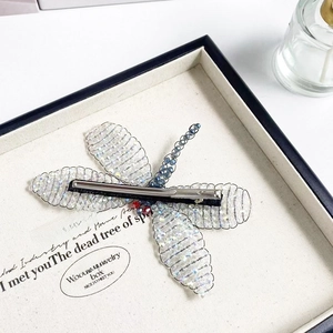 Macro shot of handcrafted woven crystal dragonfly hair clip with silver metal alligator clip