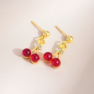 Macro view of cherry drop earrings with red beads and sparkling rhinestone leaves