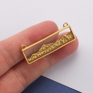 Macro shot of a golden rectangular stainless steel pendant featuring landscape patterns