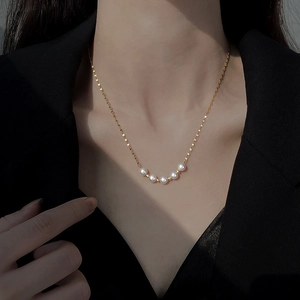 Elegant gold titanium steel necklace with six curved white pearls on a model