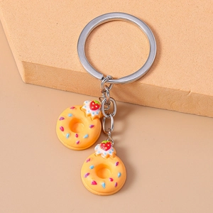 Close-up of cute 3D donut keychain with pink sprinkles and red strawberry details