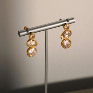 Elegant gold drop earrings with three-tier sparkling crystals on a sleek display stand