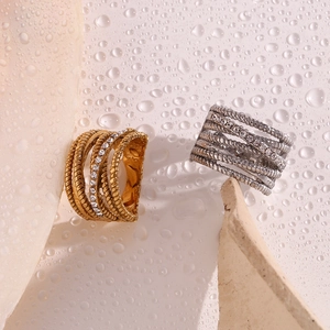 Macro shot of layered gold and silver rings with crystals on a water-droplet background