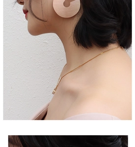 Close-up of a model wearing large pink matte hoop earrings and a thin gold chain necklace