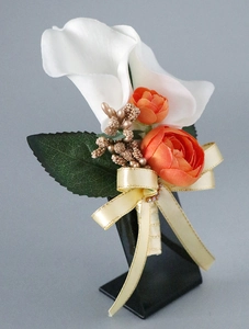 Detail of white calla lily and orange ranunculus boutonniere with golden silk ribbon