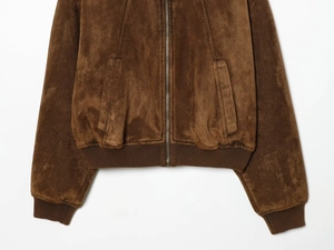 Détail d'un blouson bomber en daim marron avec fermeture éclair et ourlet côtelé