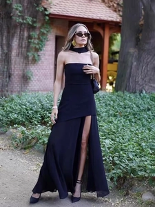 Elegant black strapless evening dress with high slit and neck strap in a garden setting